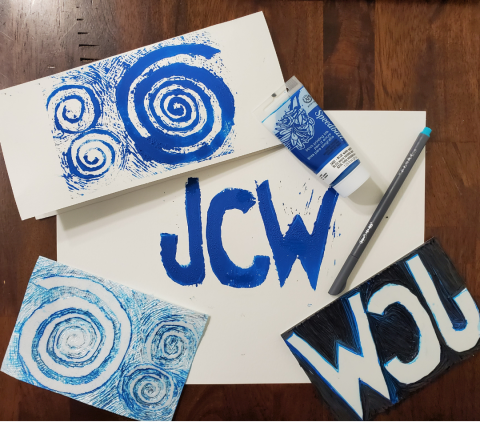 A block printed image with blue waves and a 2nd image of initials JCW printed in blue on white paper.