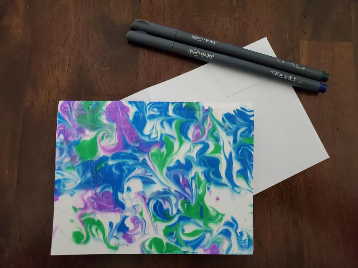 A colorful small card is displayed which features marbling with blues, greens, and purples.